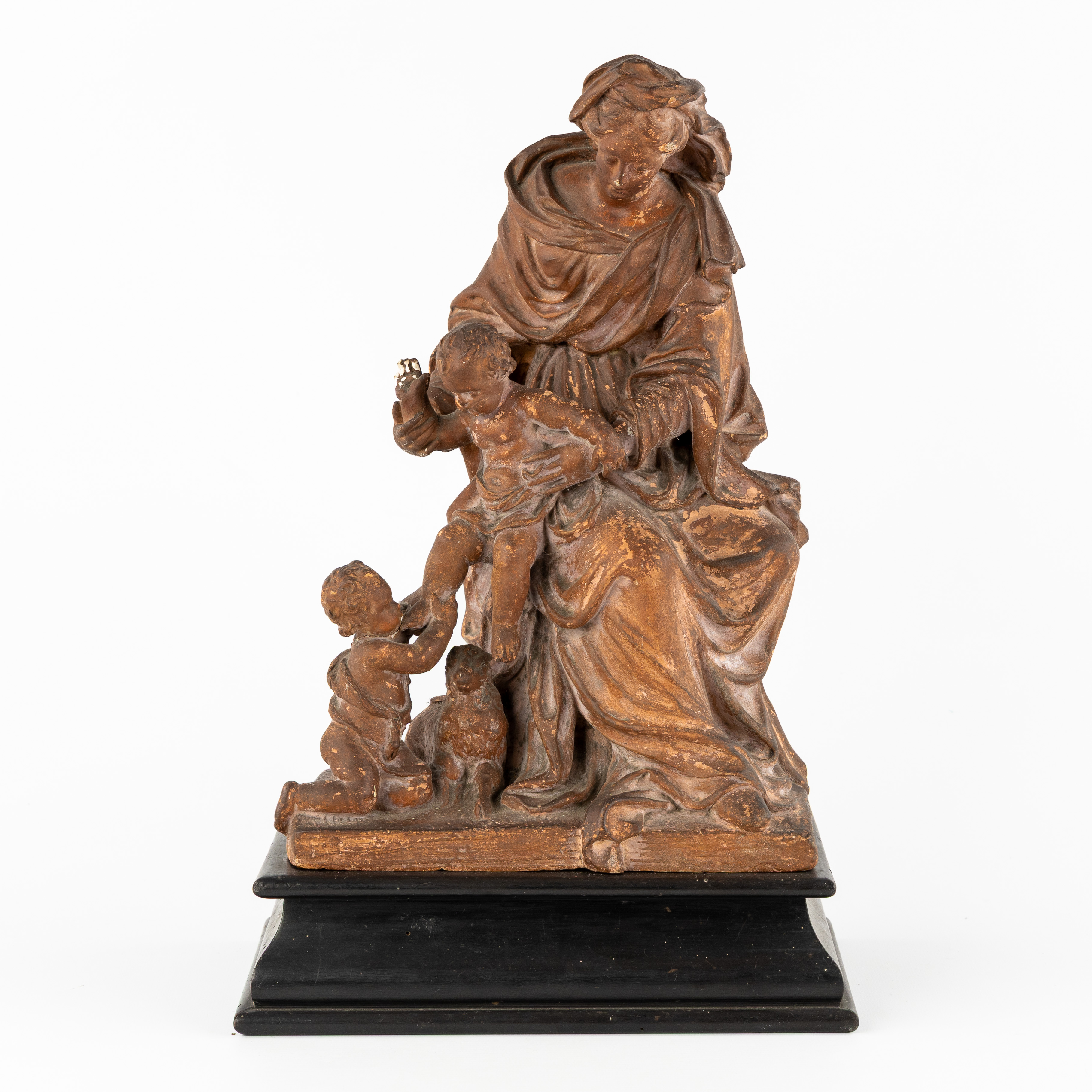 De Maagd Maria met Kind Jezus en Johannes de Doper, een beeld, gepatineerd terracotta op een houten sokkel, 18de/19de eeuw. (L:26 x W:17.5 x H:35 cm)